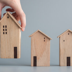 Hand choosing miniature wooden house or apartment